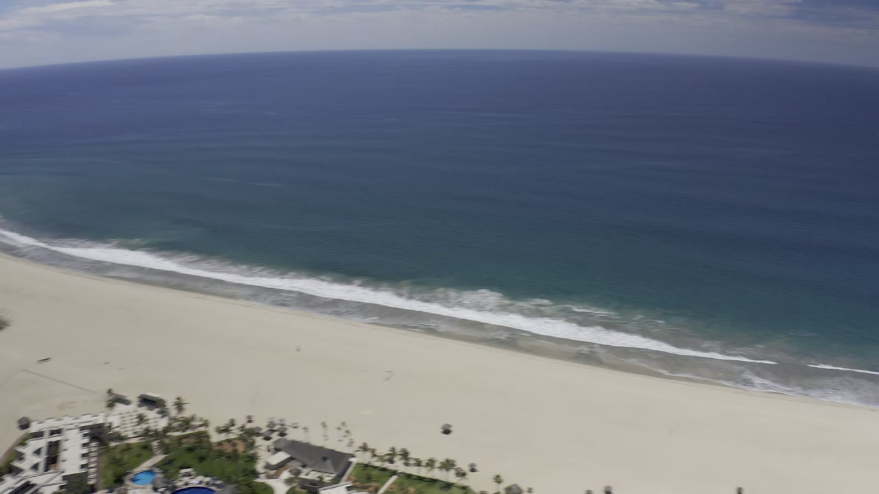 Aerial view of ocean waves meeting a sandy beach.