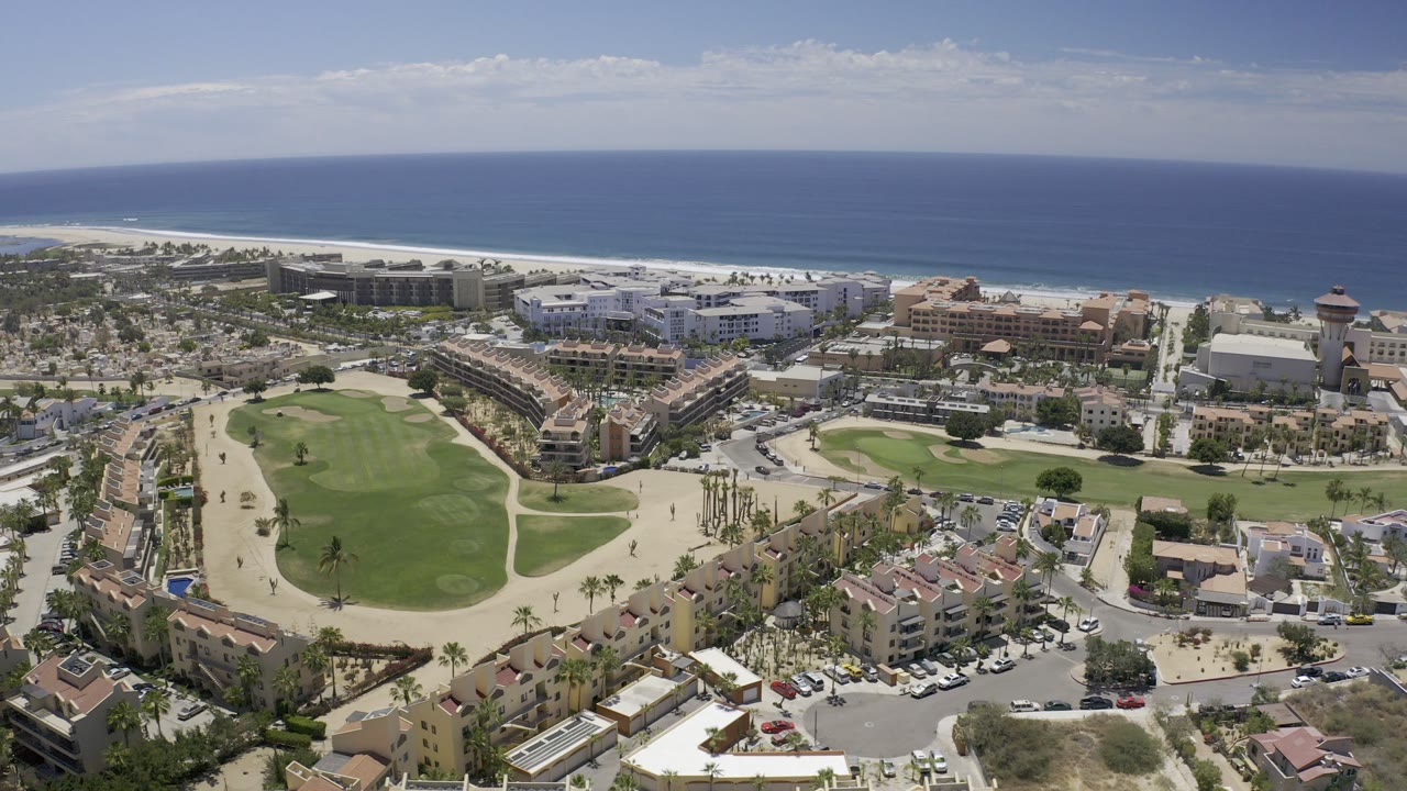 Aerial view of golf courses, resort buildings, beach, and ocean