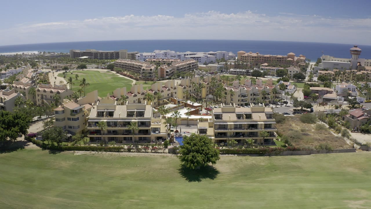 Elevated view of coastal buildings, lawns, streets, and a tower.