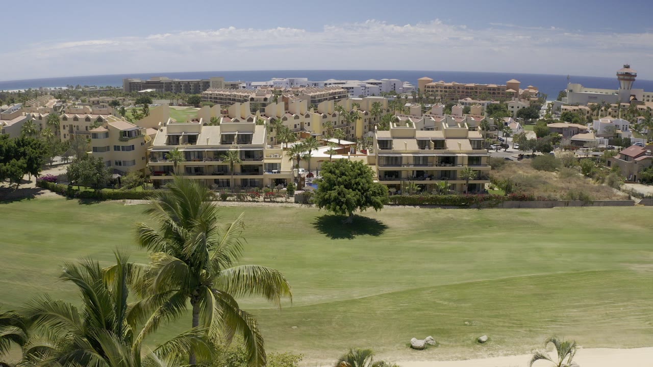 Palm-lined golf fairway with resort buildings and ocean horizon