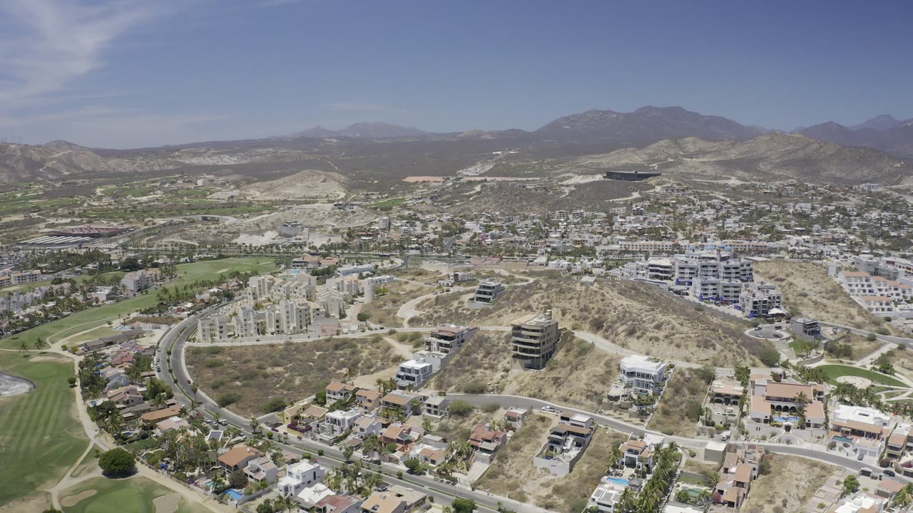 Aerial view over hillside homes, roads, and distant mountains.