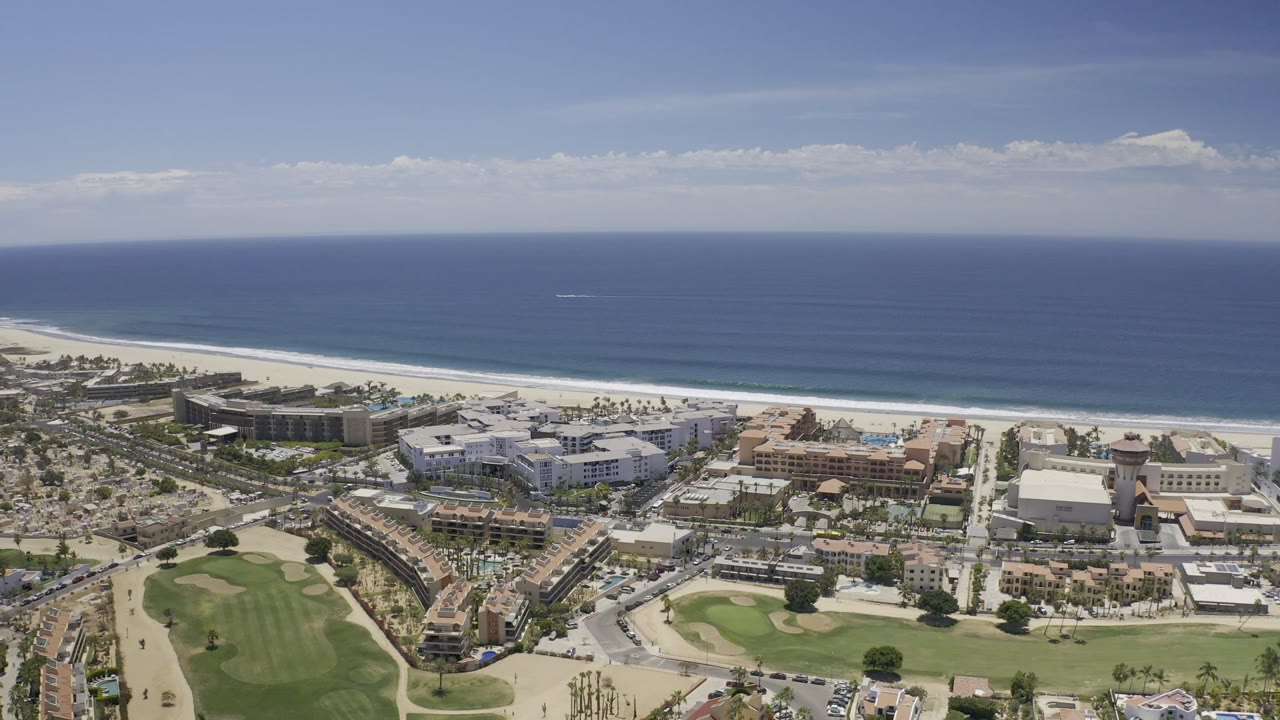 High coastal view with beach, ocean, buildings, roads, and lawns.