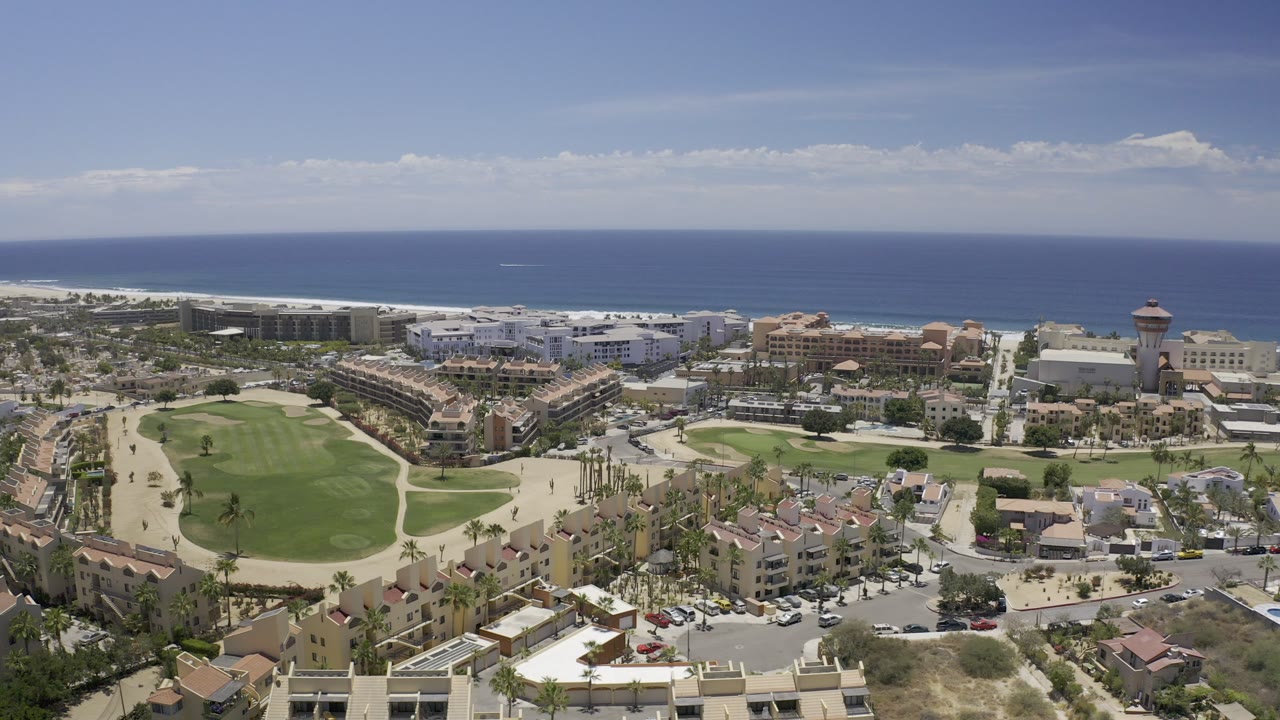 Aerial view of resort hotels, green grounds, roads, and ocean coastline.