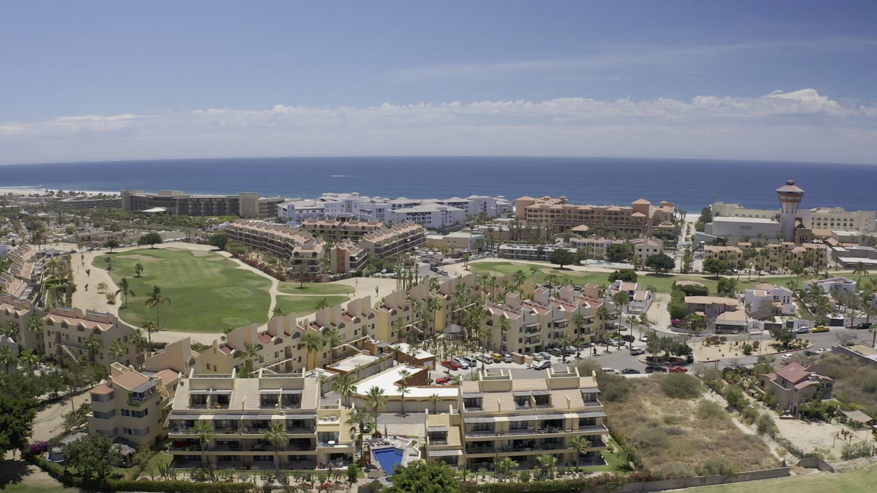 Elevated view of coastal buildings, green lawn, and ocean horizon.