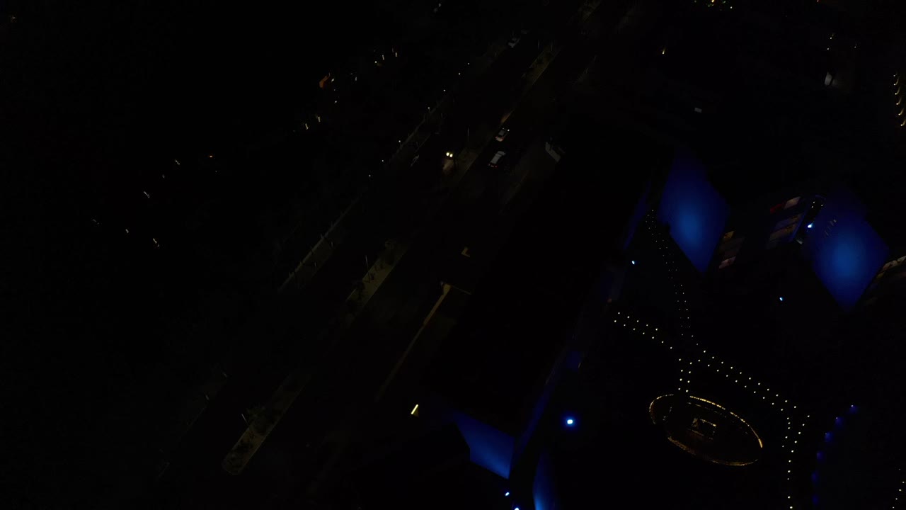 Very dark overhead city scene with blue lights and dotted building lights