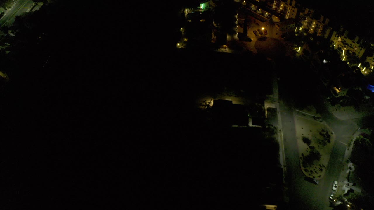 Dark aerial view of lit roads and buildings at night
