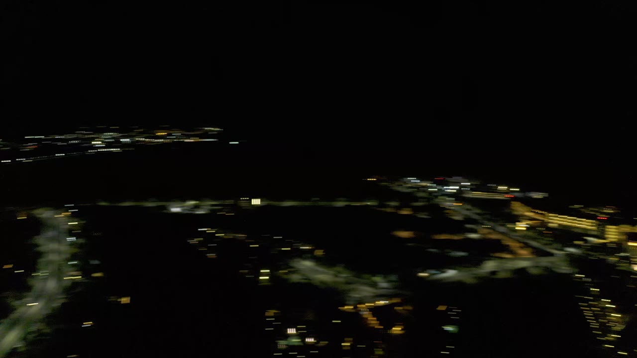 Los Cabos night frame with a brighter band of road and building lights crossing the center while the foreground stays mostly black, with no visible people.