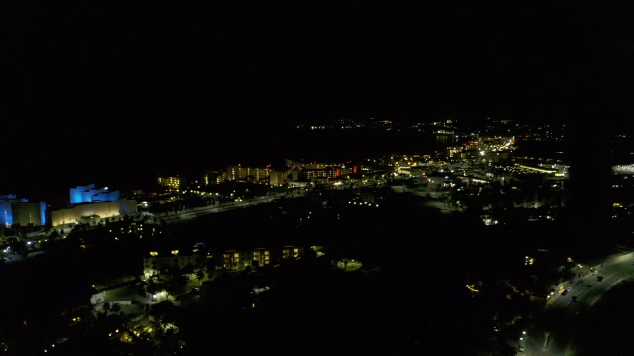 Dark aerial cityscape with distant lights and buildings.