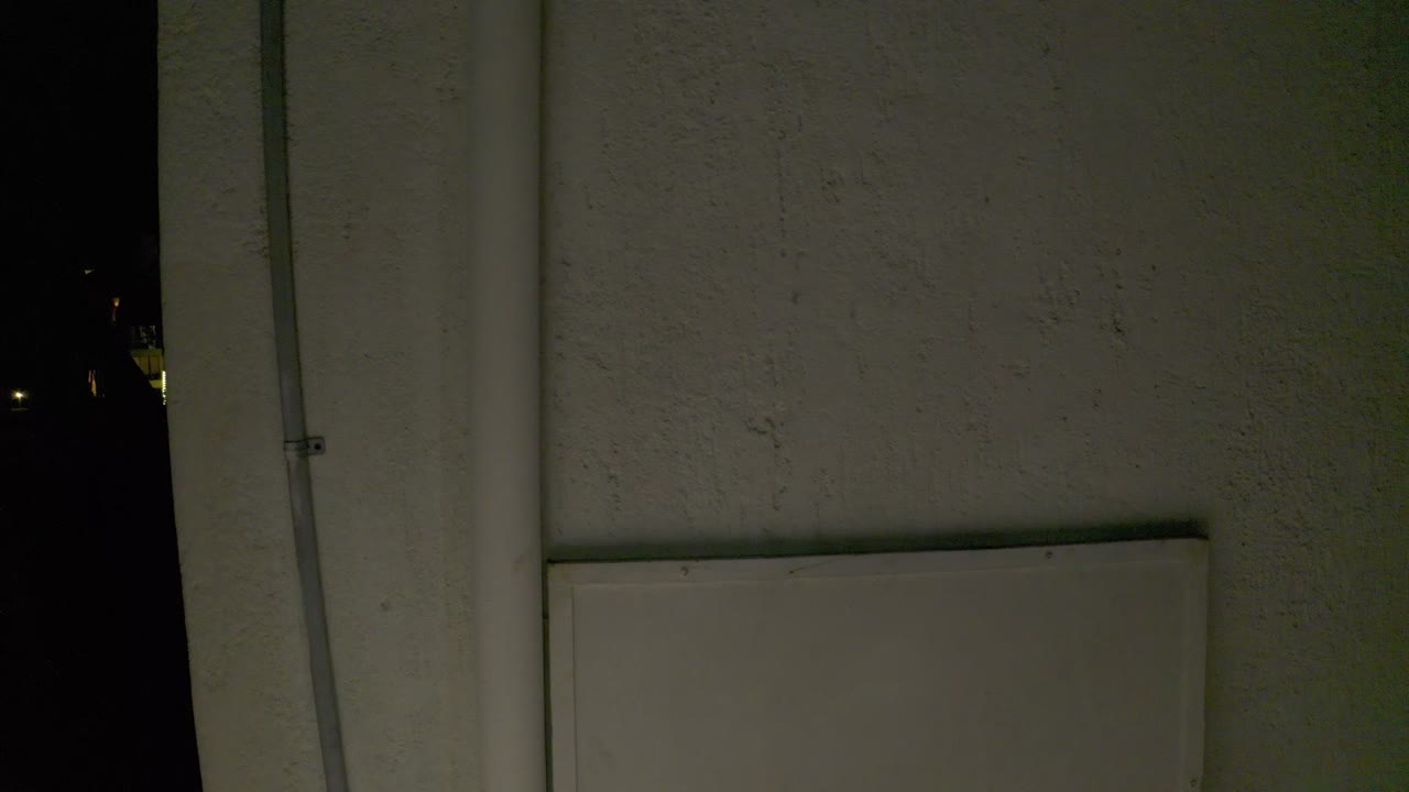 White wall surface with lower rectangular panel at night