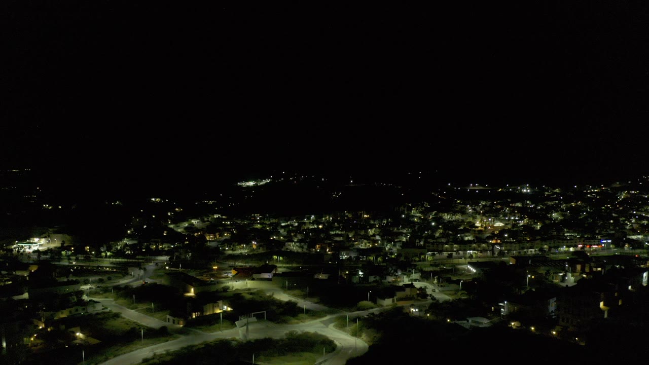 Night aerial view of lit roads and buildings under a dark sky.