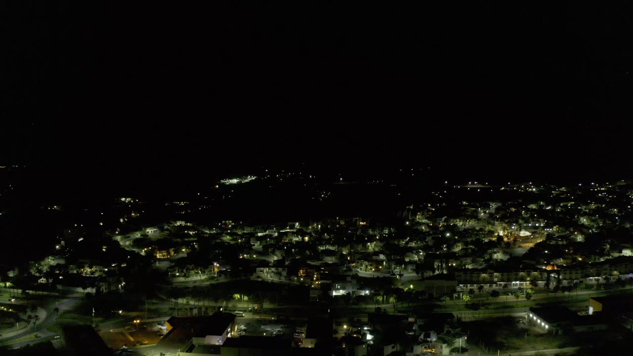 Wide nighttime city view with bright streetlights and dark horizon.