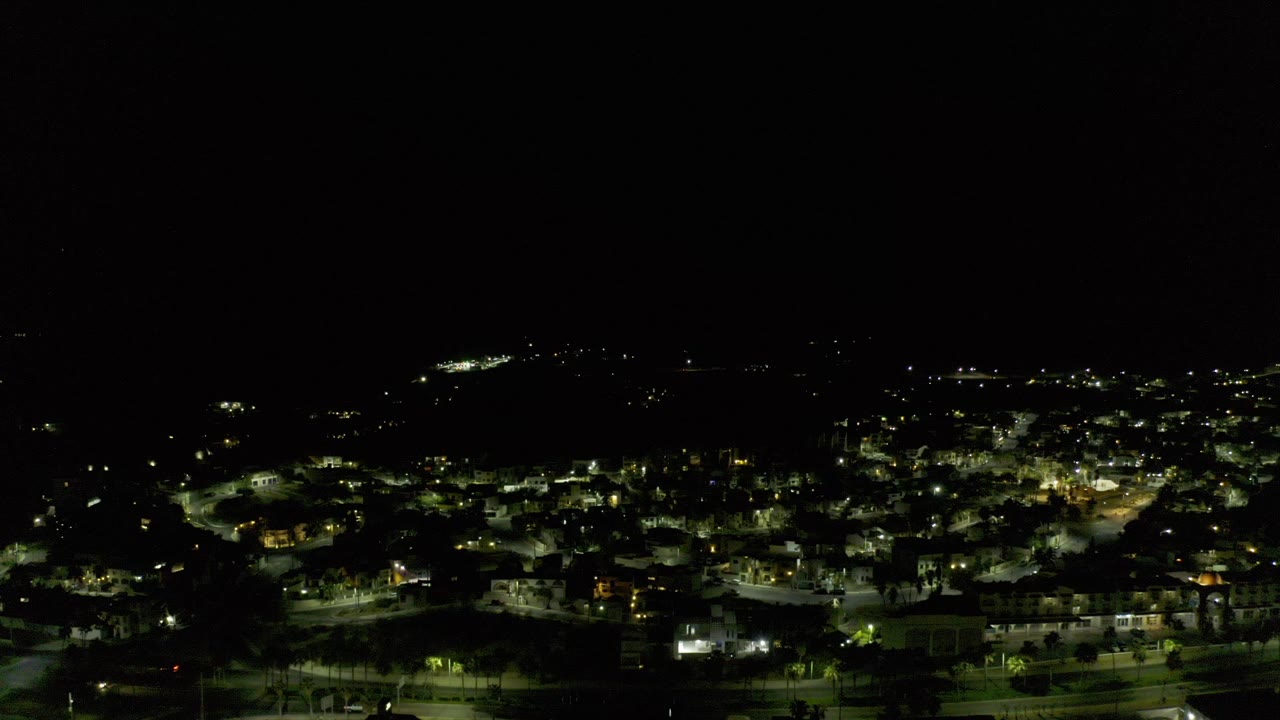 Night aerial view over a lit town with dark sky above.