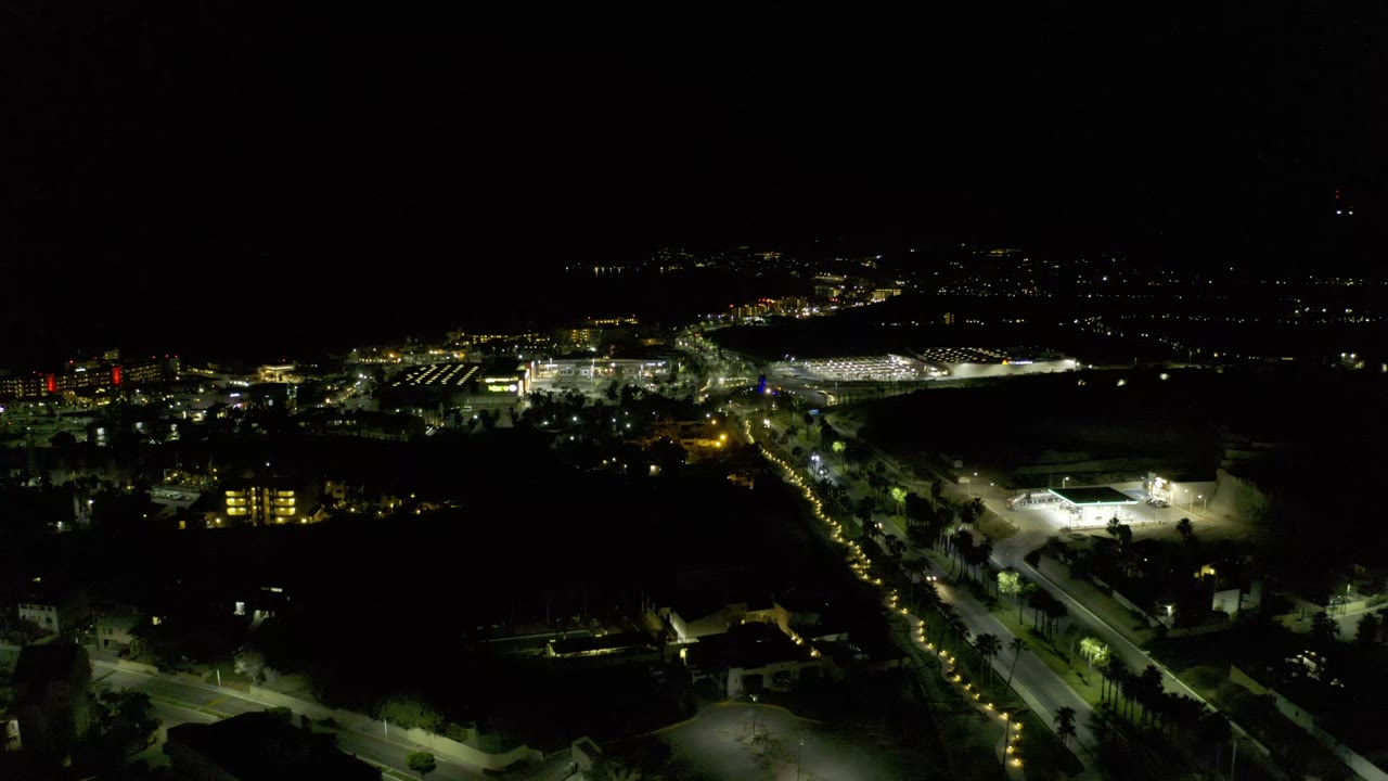 Aerial night street scene with bright building at lower right