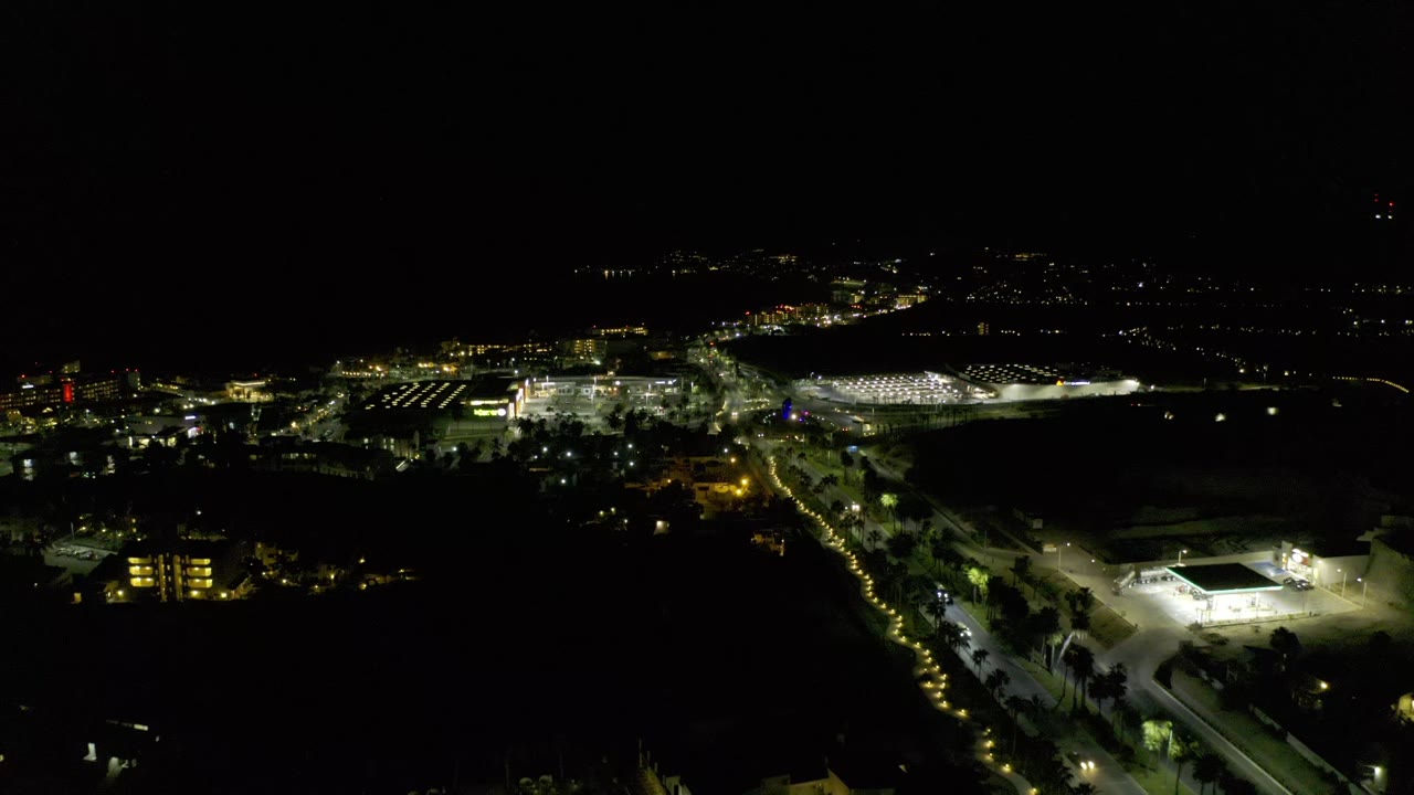 Night city panorama with distant lights and a bright low building area.