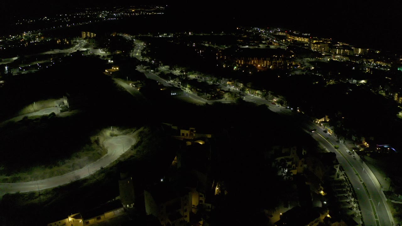 Night aerial over lit roads and dark open ground.