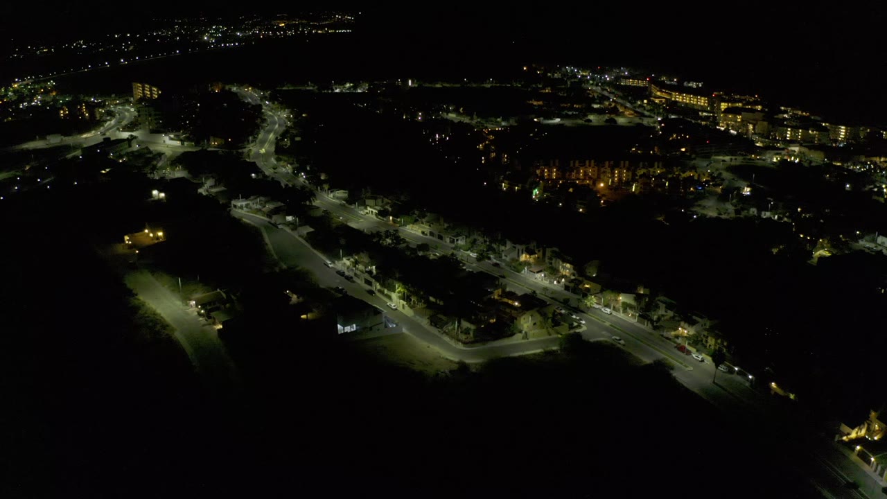 Dark aerial city view with lit roads and distant building lights.