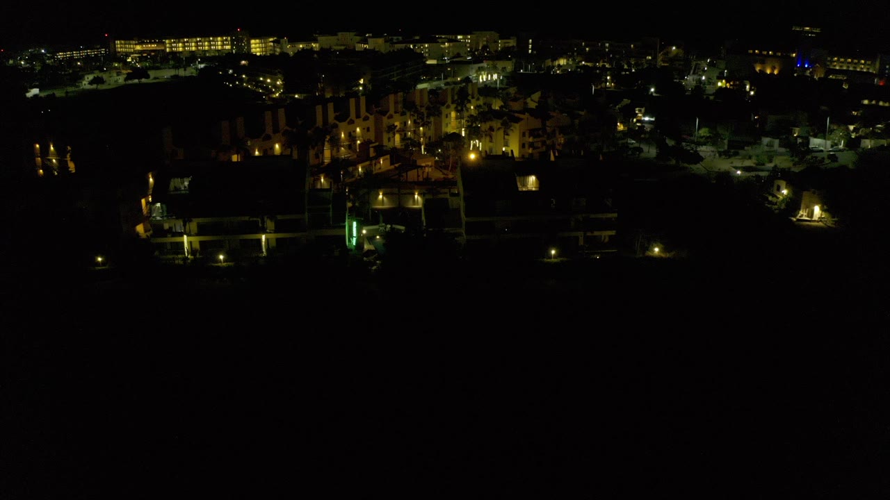 Night aerial view of illuminated buildings against a dark foreground.