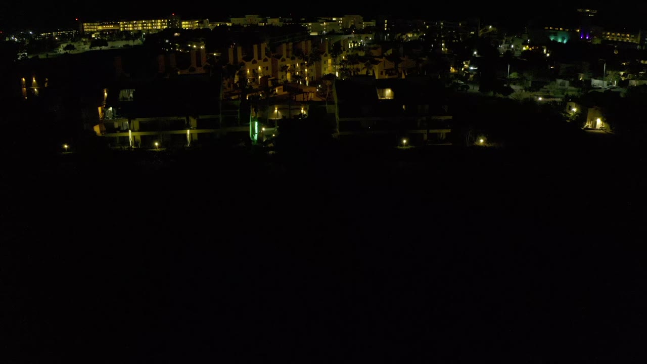 Dark drone view with low-rise lights and a mostly black lower frame.
