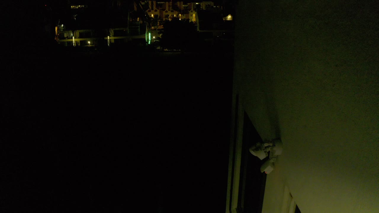 Dark nighttime exterior with lit building details and a wall edge.