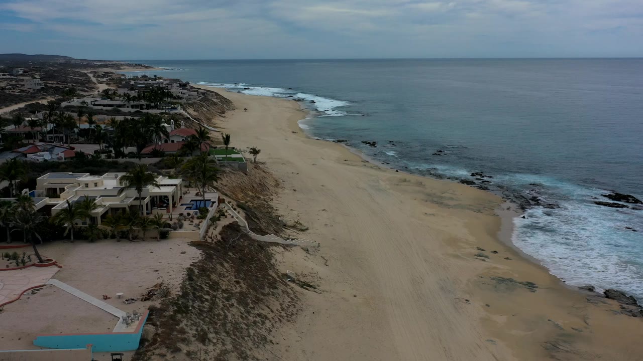 Aerial view of beach, surf, and oceanfront homes.