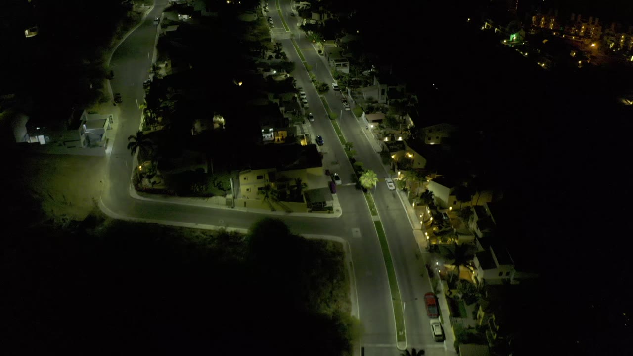 Dark aerial frame with illuminated roads and scattered homes