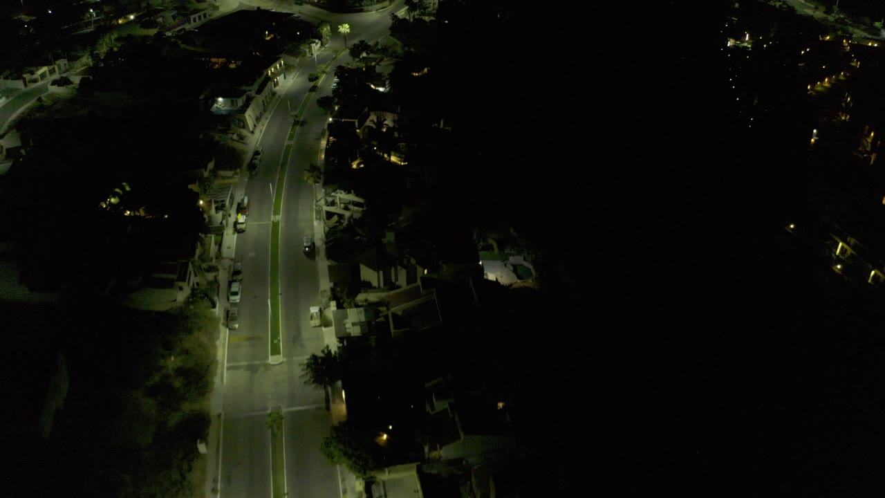 Overhead nighttime road with streetlights and dark surroundings.