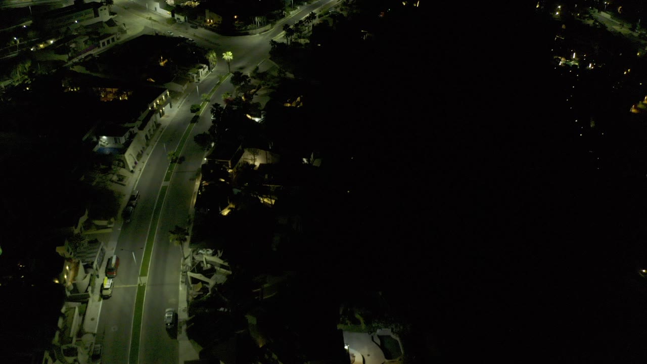 Aerial night view of a curved road lit by streetlights