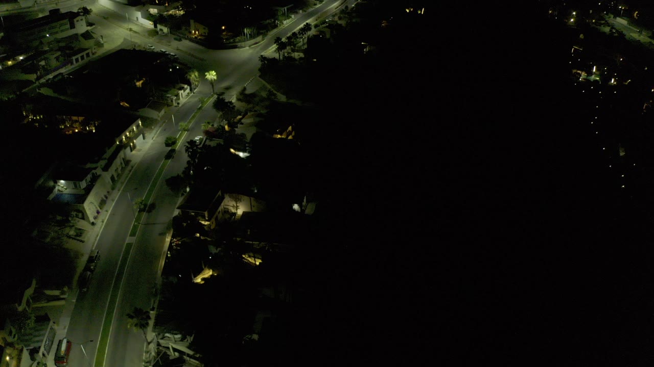 Night aerial view of a curved road and lit intersection.