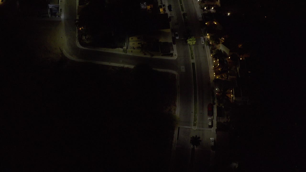 Dark aerial view of a lit road intersection at night.