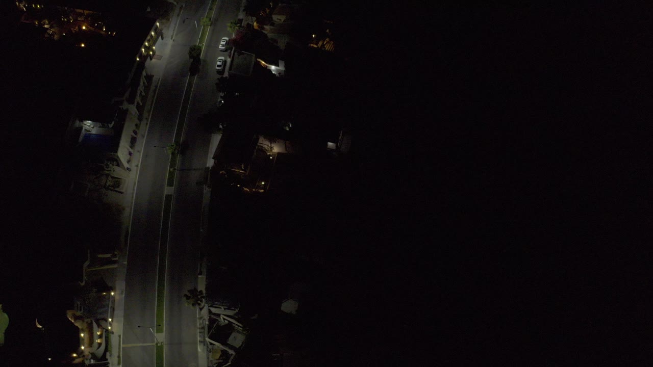 Aerial night view of a lit road beside dark open space