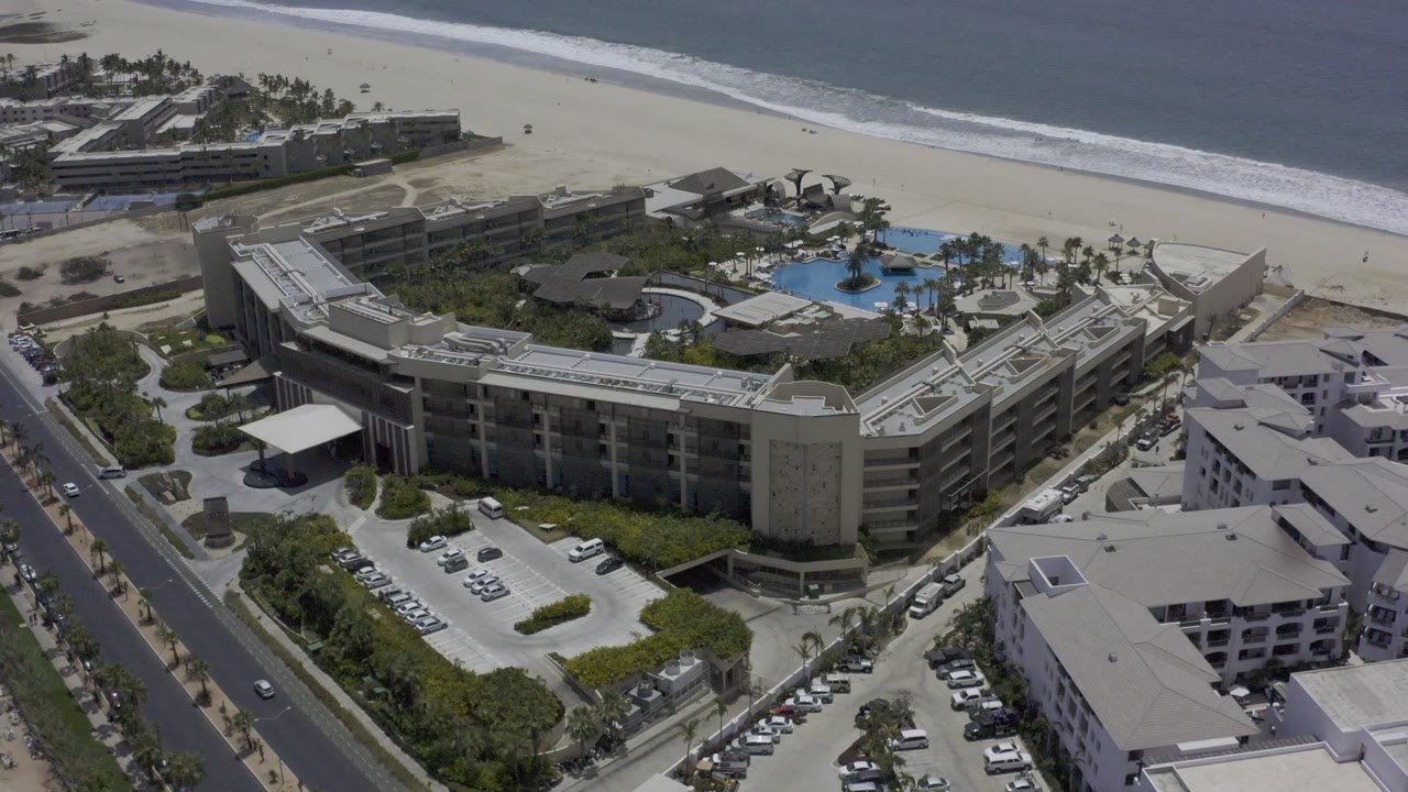 Aerial view of resort buildings, parking, beach, and ocean surf.