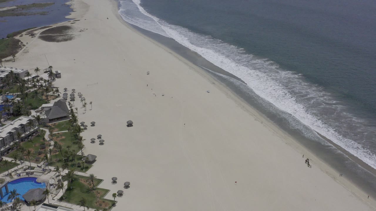 Beachfront resort area beside a wide beach and breaking surf.