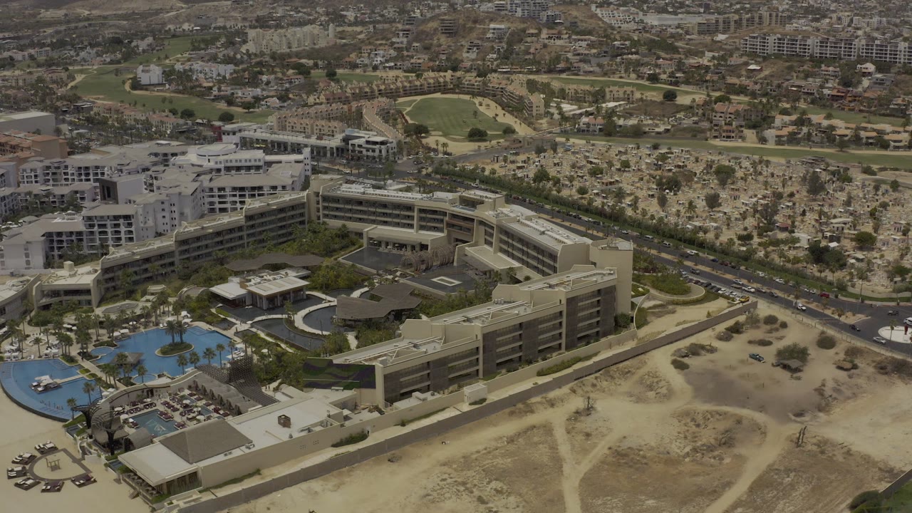 High aerial view over a modern complex with pools and surrounding roads.