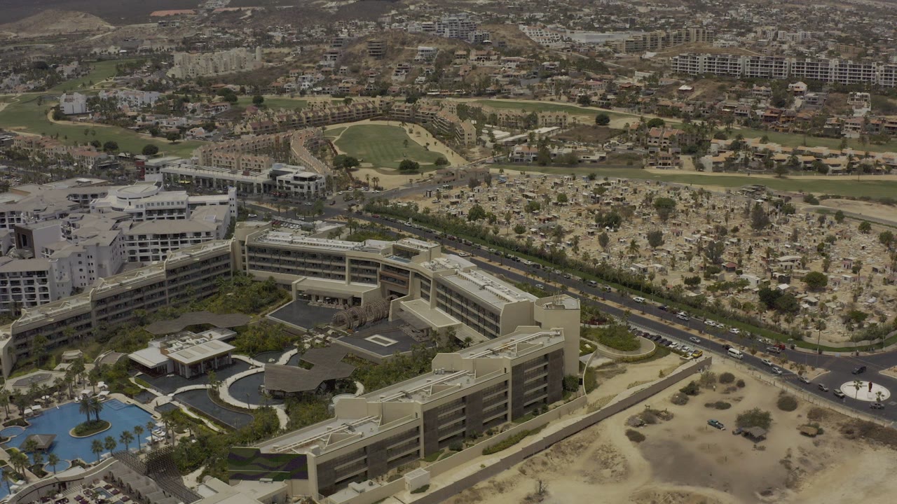 Aerial view of hotel buildings, roads, dry lots, pool, city blocks, and hills.