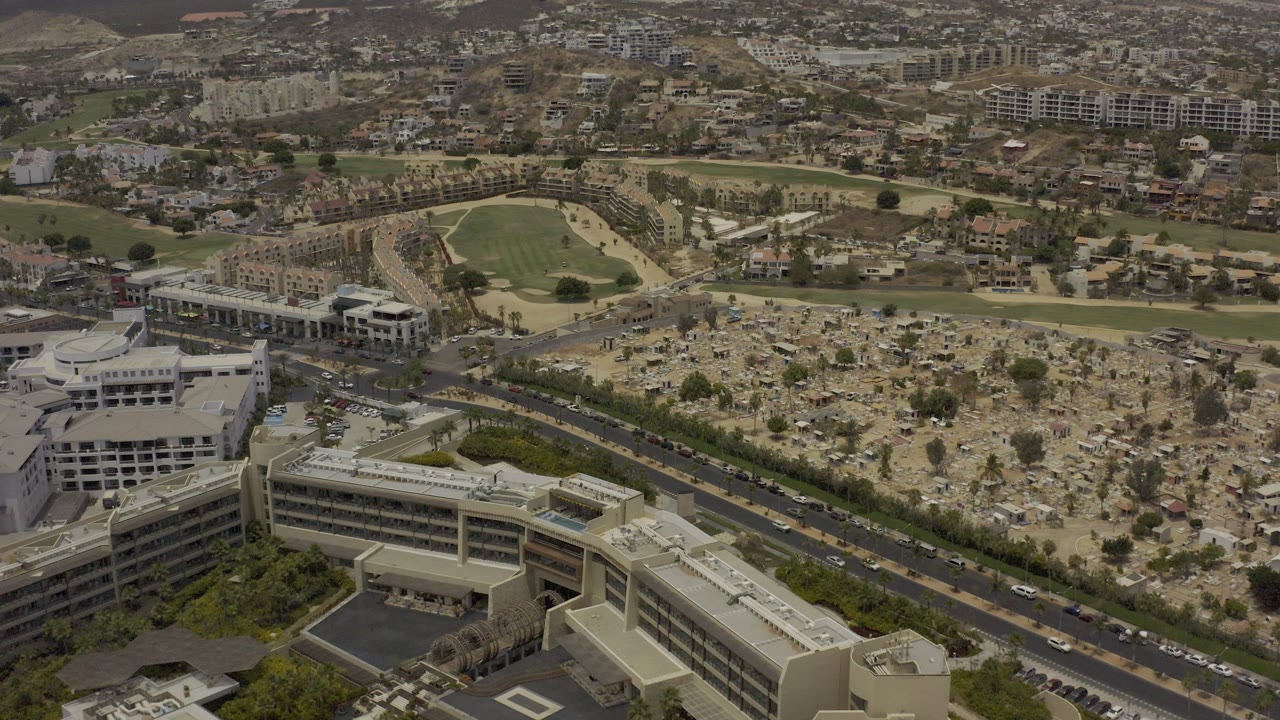 High aerial view of roads, large buildings, dry open land, housing, and hills.