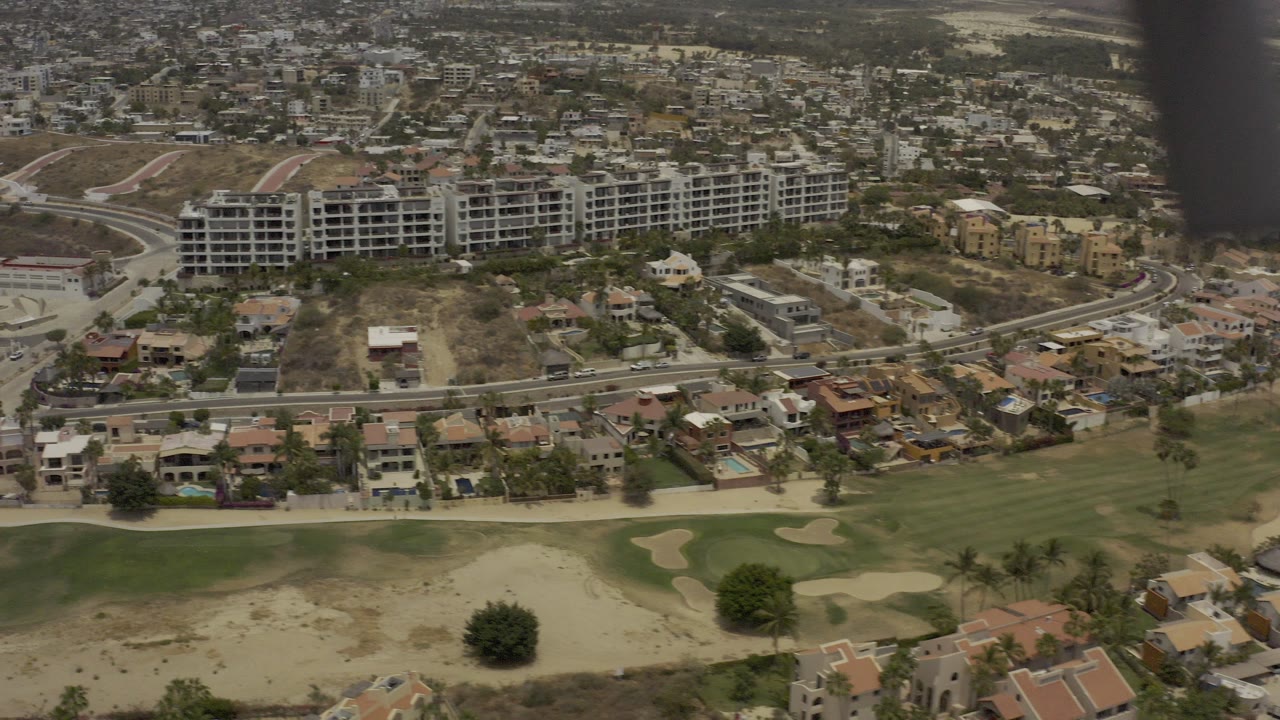 Aerial view of golf fairways, homes, roads, and unfinished apartment buildings.