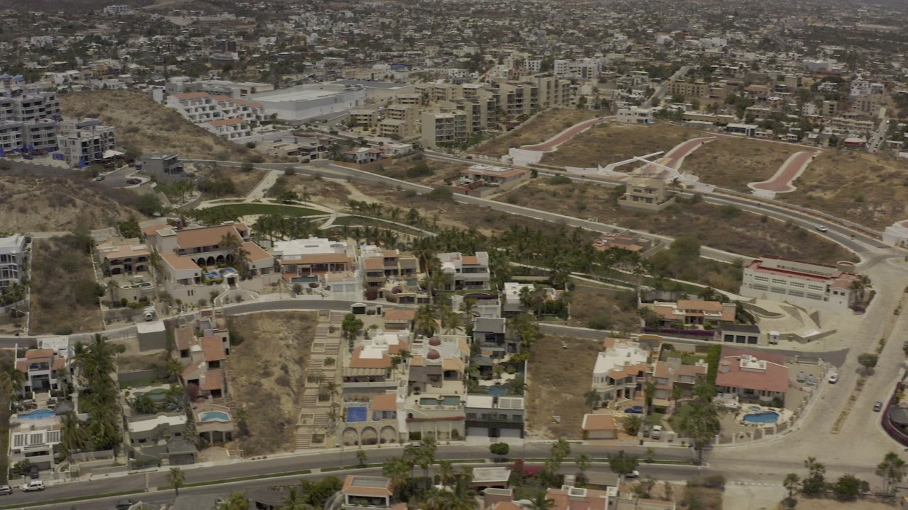 Aerial view of hillside roads, homes, pools, and apartment buildings.