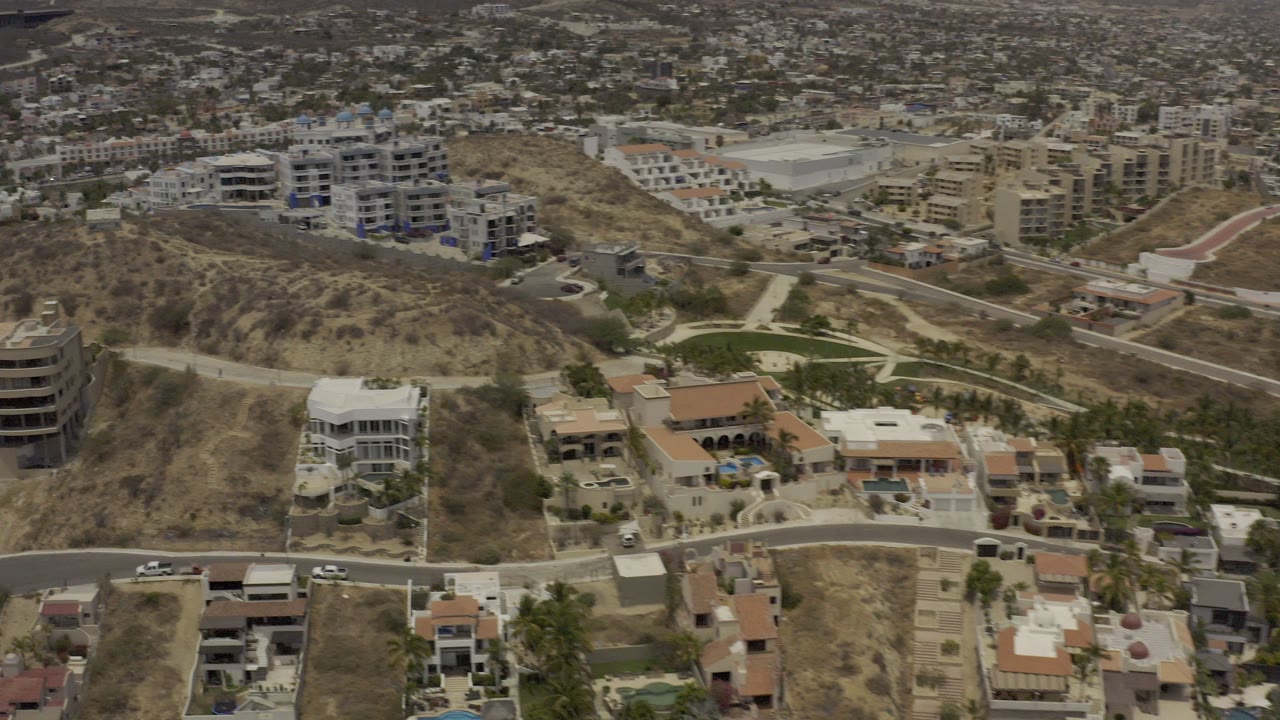 Aerial view of dry hills, homes, roads, and distant buildings