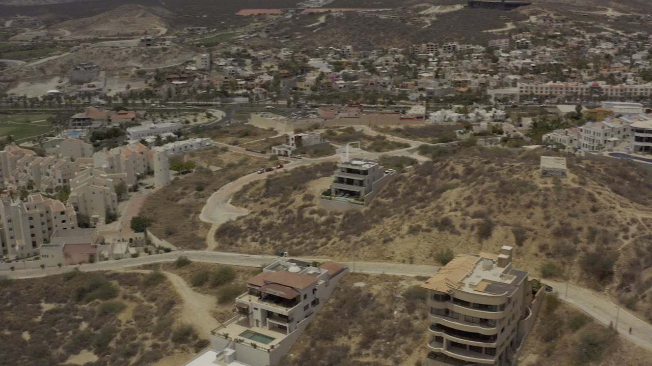 Aerial view of hillside homes, roads, and dry terrain.