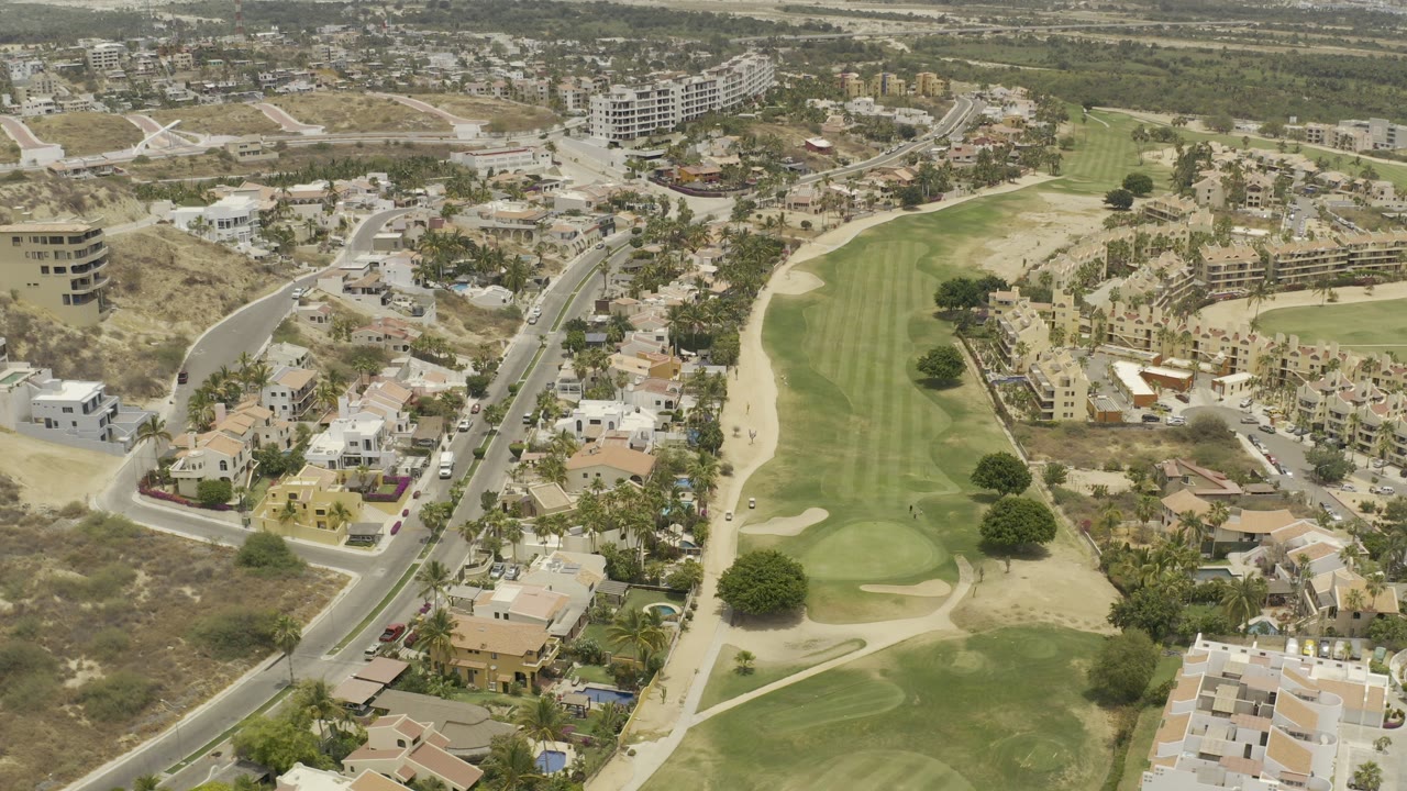 Aerial view of a golf course beside roads and homes