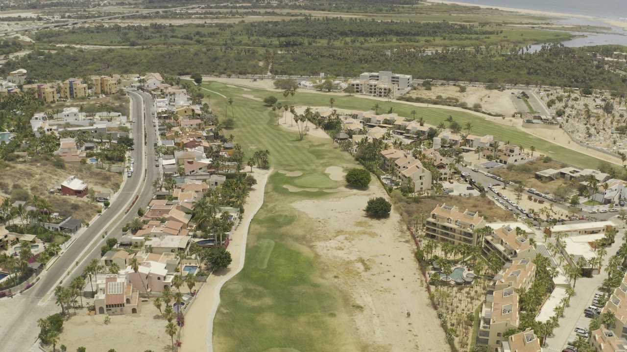 Aerial view over golf course, road, homes, and coastline.