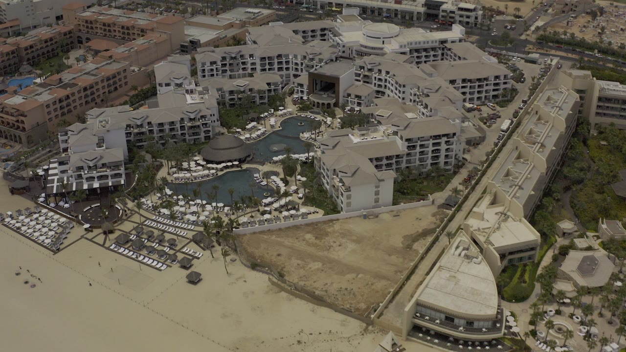Aerial view of a large beachfront resort with pools and hotel buildings.