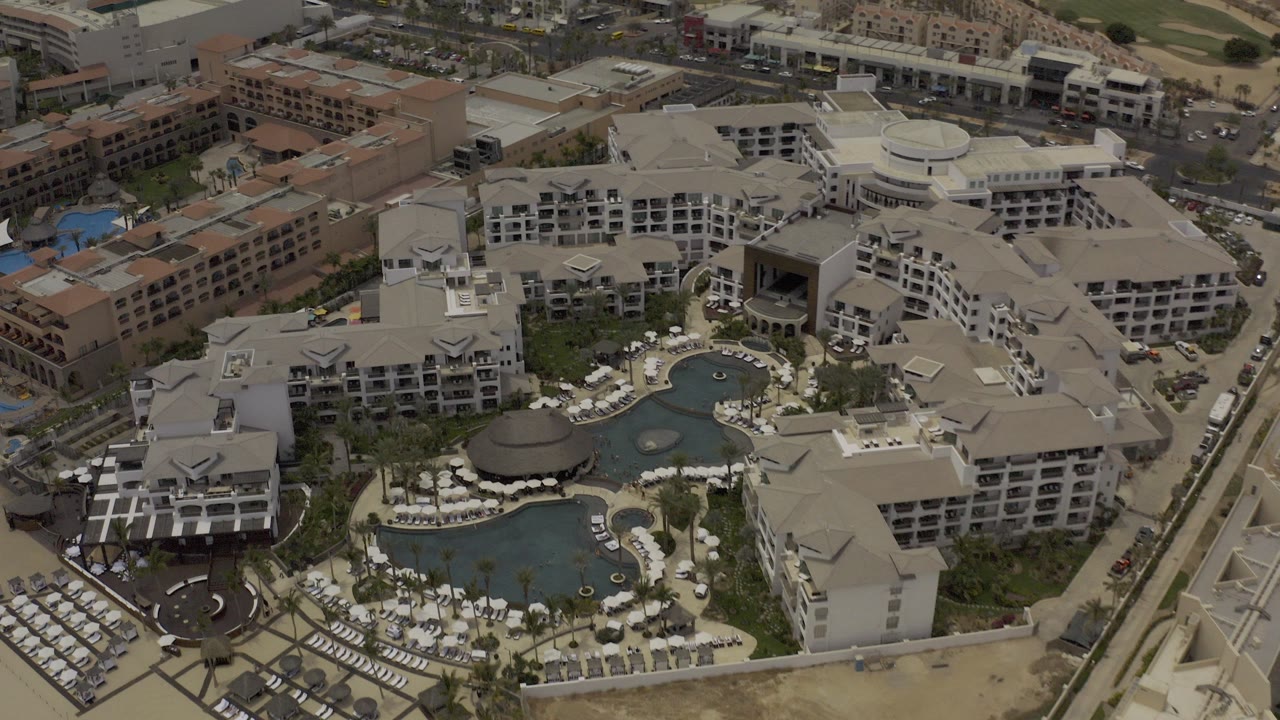 High aerial view of a resort complex with pools and pale roofs.