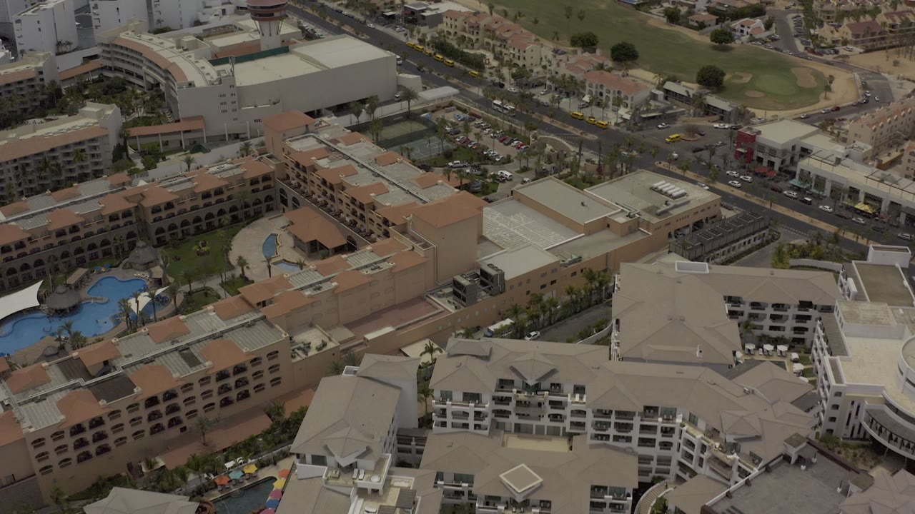 Overhead view of modern buildings, roads, vehicles, and pool courtyards.