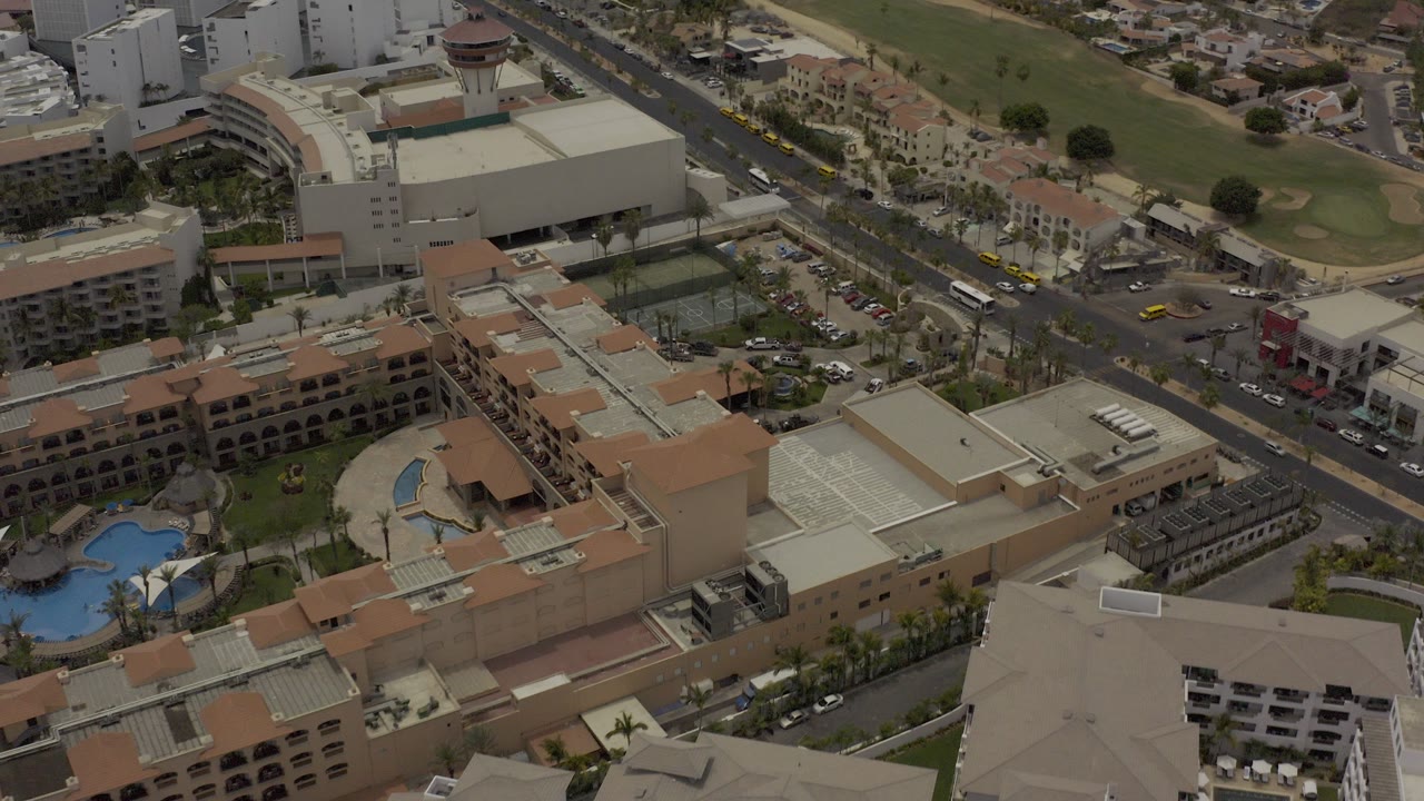 Aerial view of a large hotel complex, pools, roads, and towers.