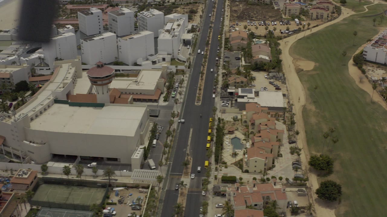 Aerial view of buildings, road, golf course, and homes.