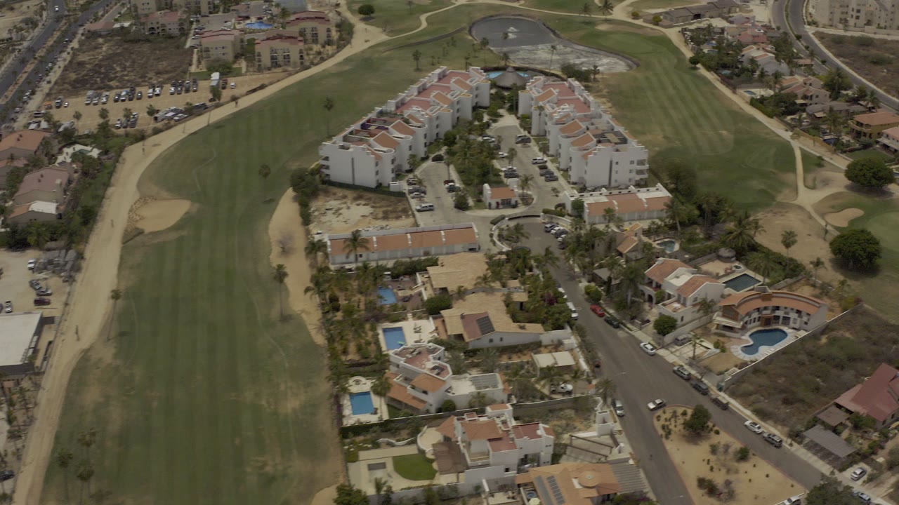 Aerial view of condos beside a golf fairway and road.