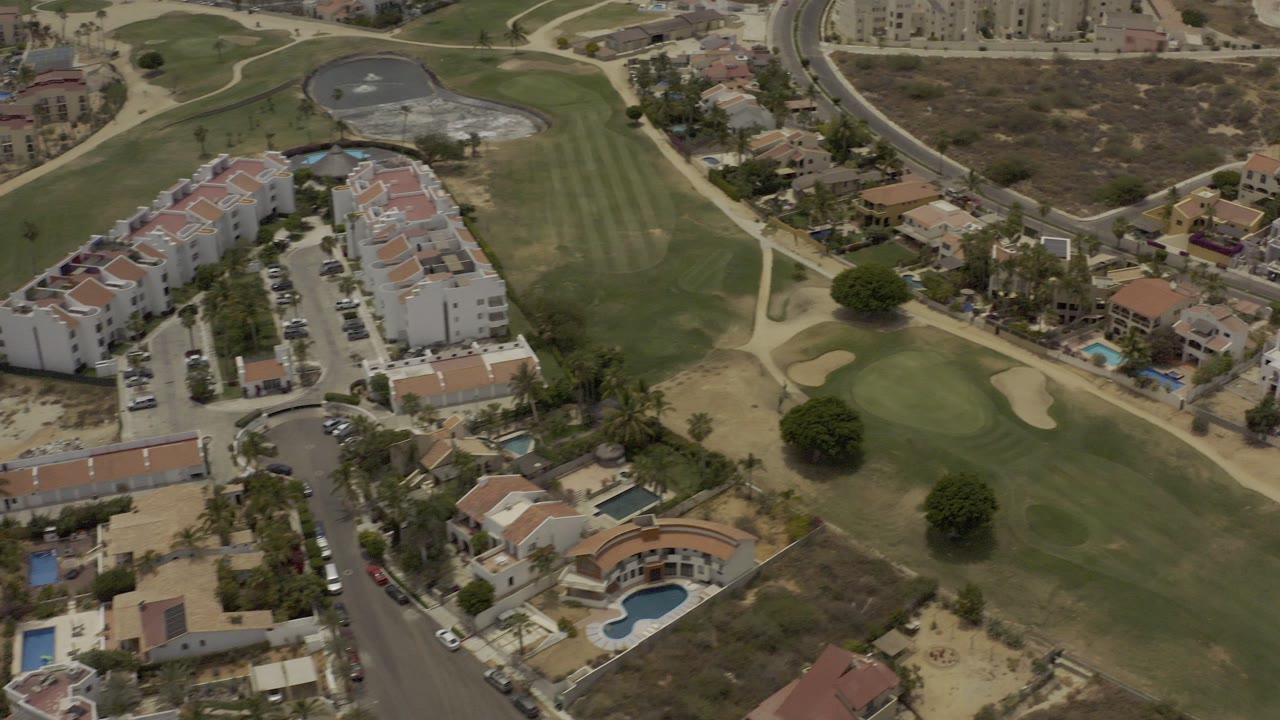 Aerial view of homes beside a green golf course and roads.