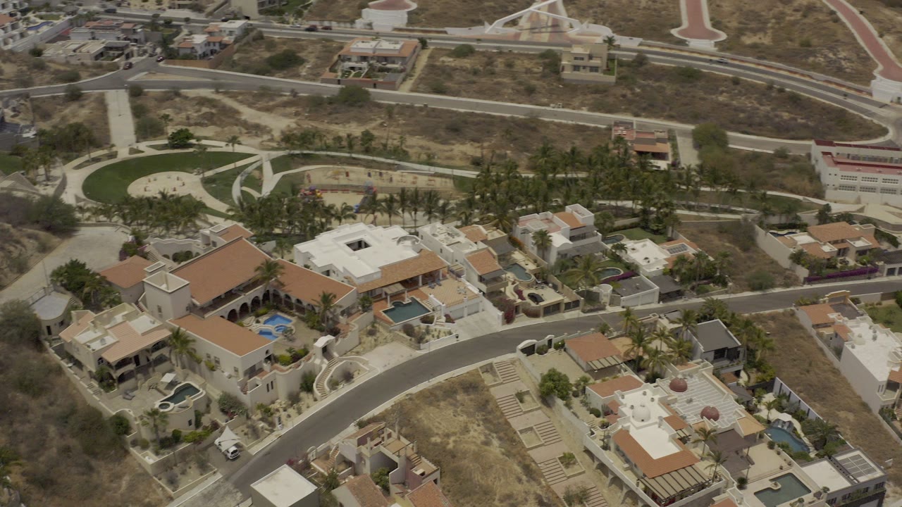 Aerial view of luxury homes, roads, pools, and dry open terrain.
