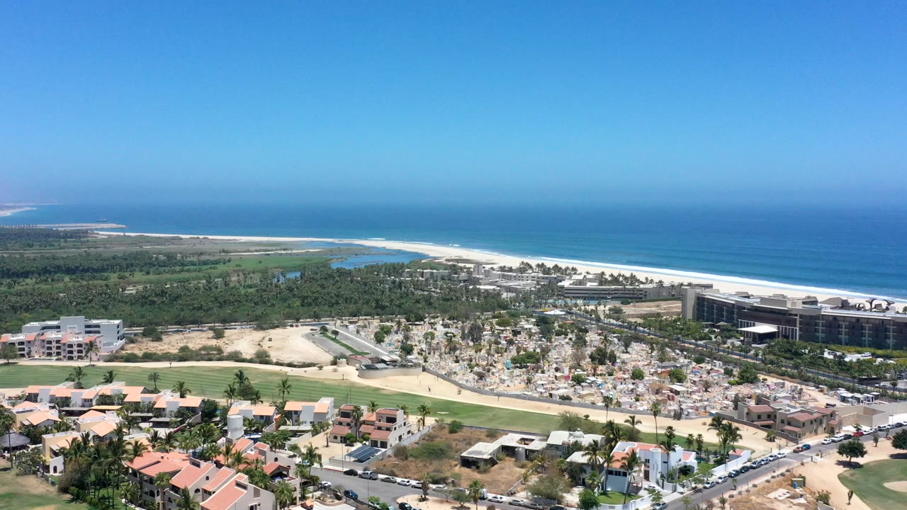 High coastal view of town, beach, blue sea, and resort buildings.